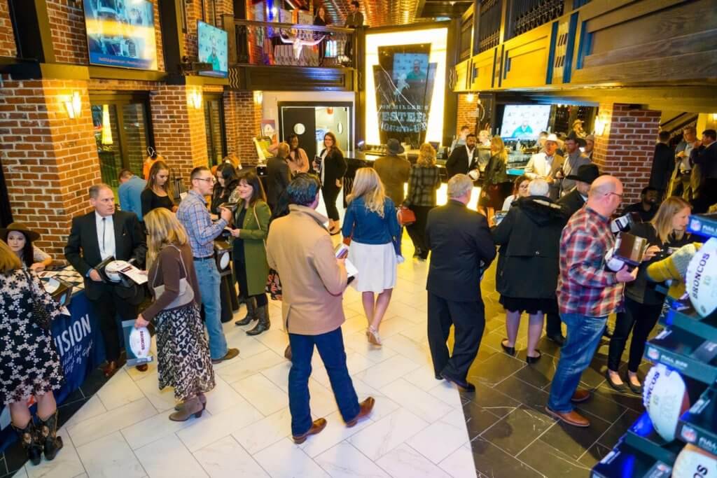 Guests mingling at Von Miller's Western Hound-Up charity event inside Ironworks Denver